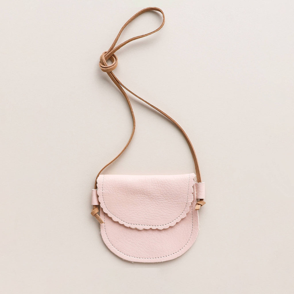 Small pink handbag with a strap on a light beige background